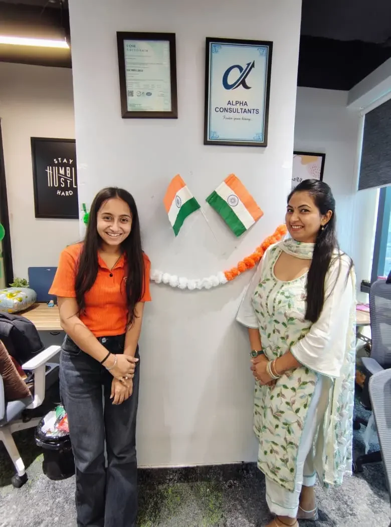 Alpha Consultants colleagues in the office beneath the company sign